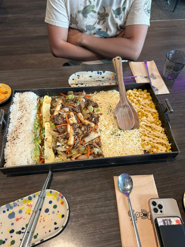 Shared meal tray with rice, meat, and sides